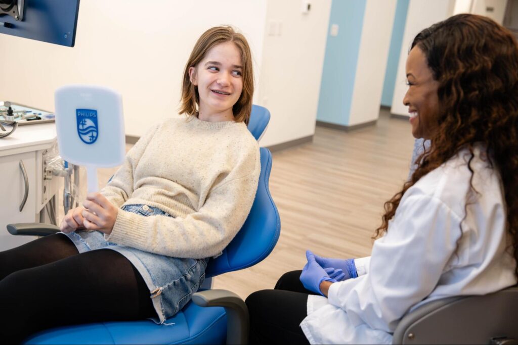 Girl smiling in orthodontic chair with orthodontist, showcasing friendly consultation atmosphere at MyFamily Orthodontics, emphasizing braces and clear aligners options in Orlando.